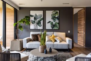 Modern living room featuring a gray accent wall with botanical art above a light gray sofa. A fiddle-leaf fig and snake plant add natural elements, complementing the DIY home accent wall's design.