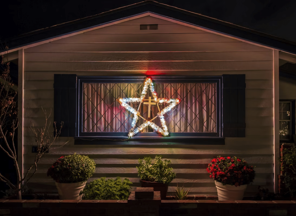 House with Christmas light decoration: a star in the window, flower pots below. A cozy holiday scene.