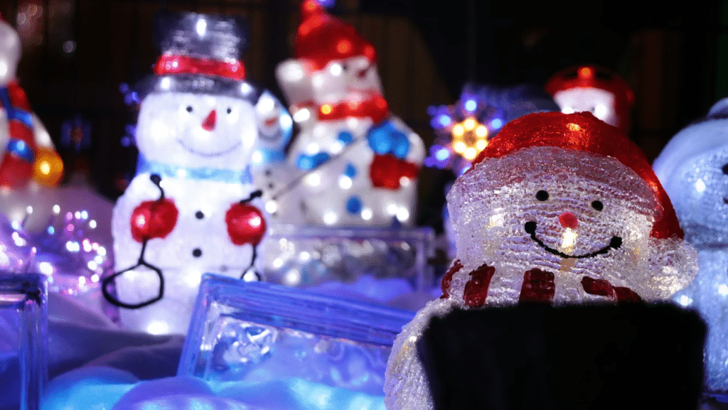 Glowing snowman Christmas light decorations bring holiday cheer. Illuminated snowmen with red hats and scarves add festive charm to home Christmas light decorations.